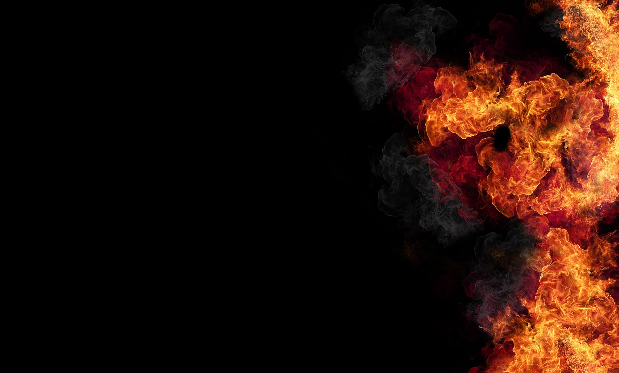 Abstraktes Bild von wirbelnden roten und orangefarbenen Flammen vor einem schwarzen Hintergrund.